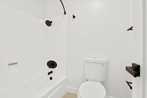 A white toilet in a bathroom with a white tub.