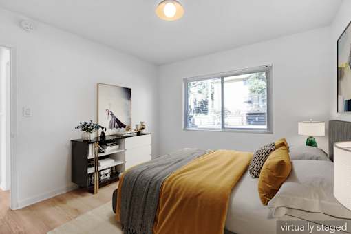 A bedroom with a bed, nightstand, and a painting on the wall.