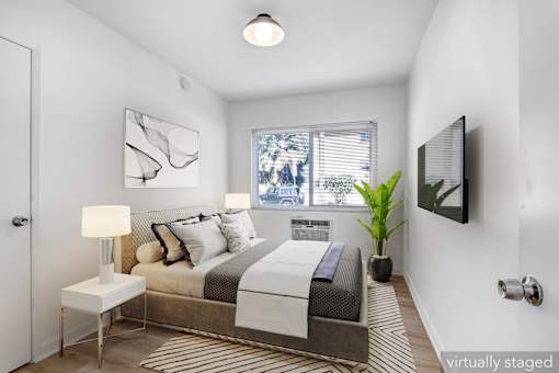 A bedroom with a bed, nightstand, lamp, and a window.
