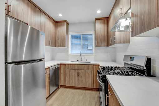 A modern kitchen with wooden cabinets and a stainless steel refrigerator.