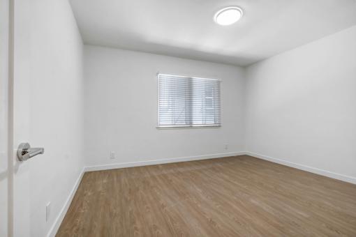 A room with a window and wooden flooring.