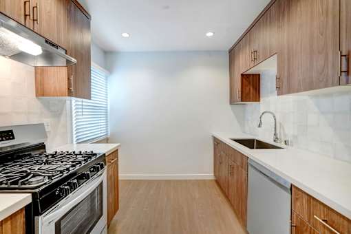 A modern kitchen with a stove, sink, and cabinets.