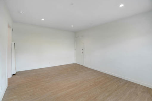 A room with wooden flooring and white walls.