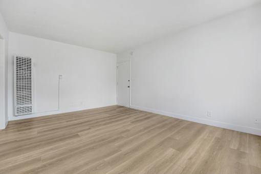 A room with wooden flooring and white walls.
