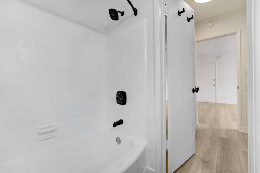 A white bathroom with a tub and a door.