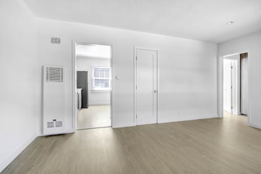 A white room with a wooden floor and a mirror on the wall.