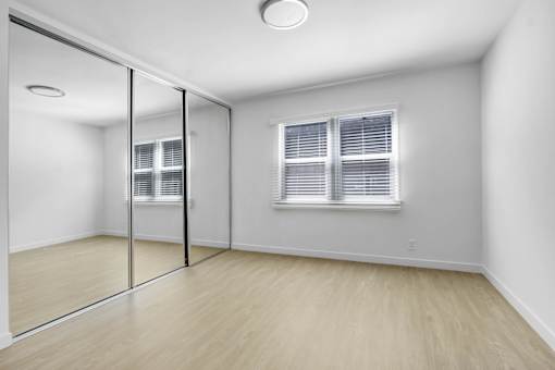 A room with a sliding glass door and a window with blinds.