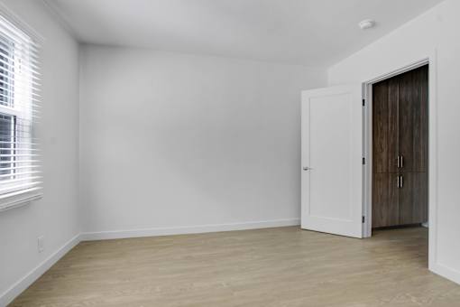 A room with a white door and a window with blinds.