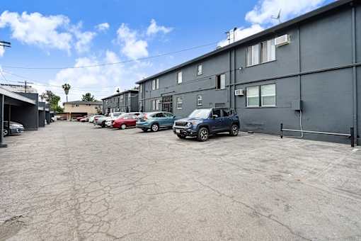 A parking lot with several cars and a building in the background.