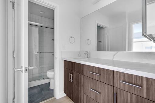 A bathroom with a white counter top and brown drawers.