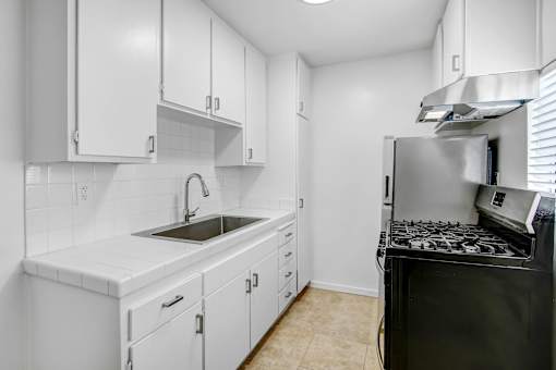 A kitchen with white cabinets and a black stove top oven.