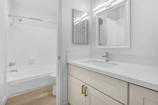 A white bathroom with a tub, sink, and mirror.