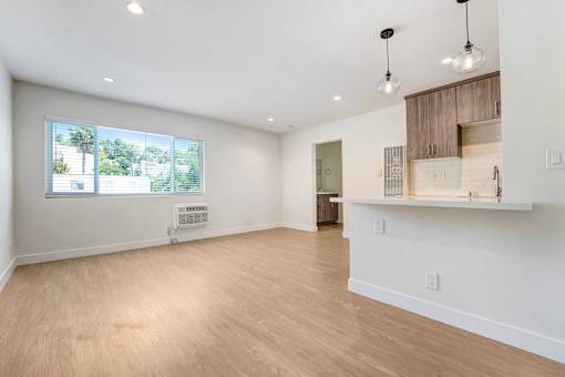 A spacious room with wooden flooring and a large window.