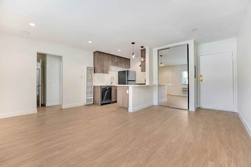 A spacious living room with a fireplace and a kitchen area in the background.