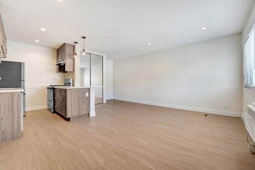 A spacious kitchen with wooden floors and white walls.