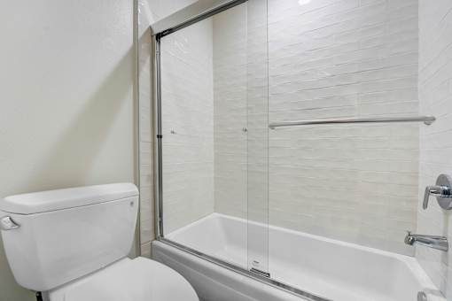 A white toilet sits next to a glass shower door.