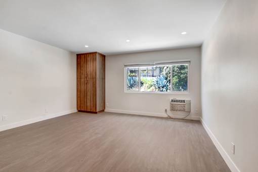 A room with a window and a wooden cabinet.