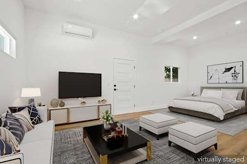 A modern living room with a large bed and a flat screen TV.