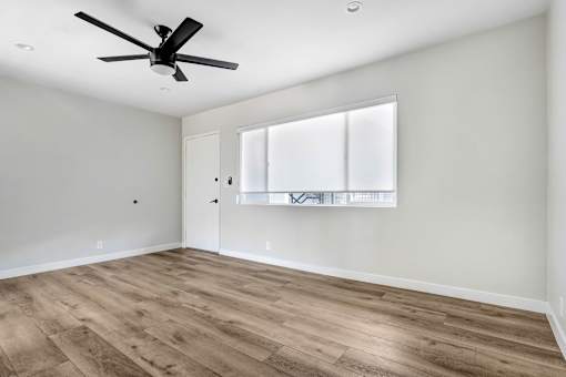 A room with a ceiling fan and wooden flooring.