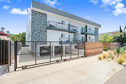 A modern two-story house with a white and grey exterior and a black metal fence.