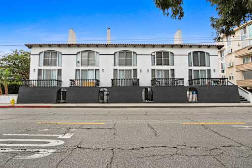 A white building with black railings and a fire hydrant in front.