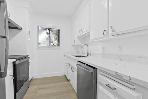 A modern kitchen with white cabinets and a marble countertop.
