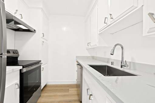 A modern kitchen with white cabinets and a black oven.