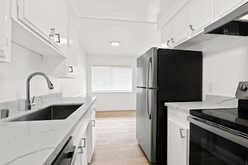 A black refrigerator in a kitchen with white cabinets.