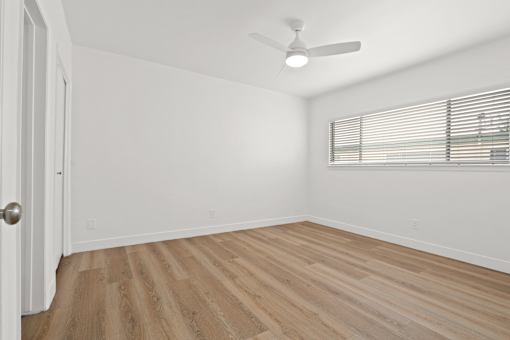 A room with a ceiling fan and wooden flooring.