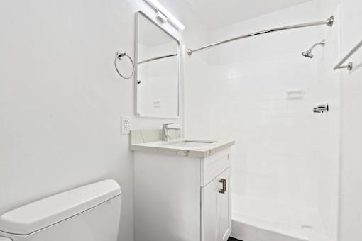 A white bathroom with a toilet, sink, and shower.