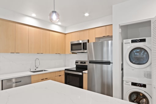 a white kitchen with stainless steel appliances and a washing machine