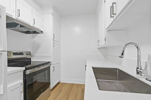 A modern kitchen with white cabinets and stainless steel appliances.