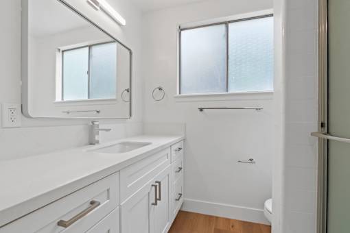 A white bathroom with a sink, mirror, and shower.