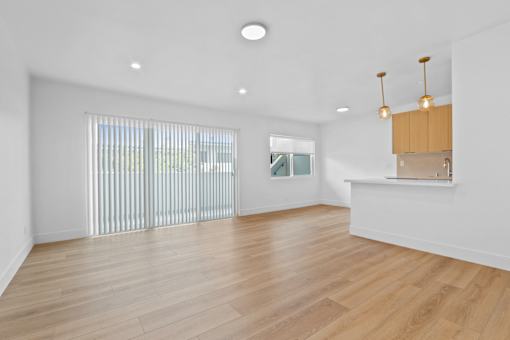 A room with wooden floors and a window with blinds.