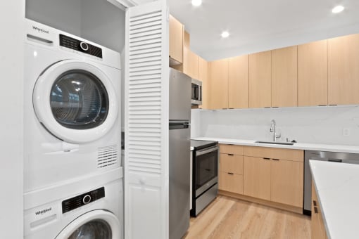 a white washer and dryer in a kitchen with wooden cabinets
