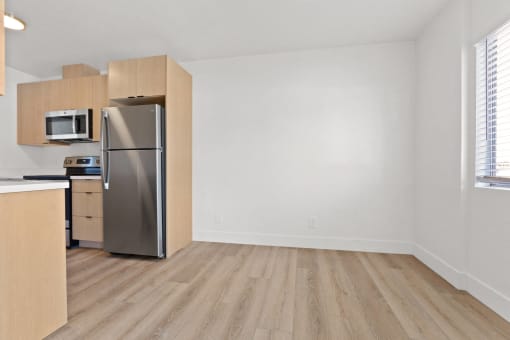an empty apartment living room with a refrigerator and microwave