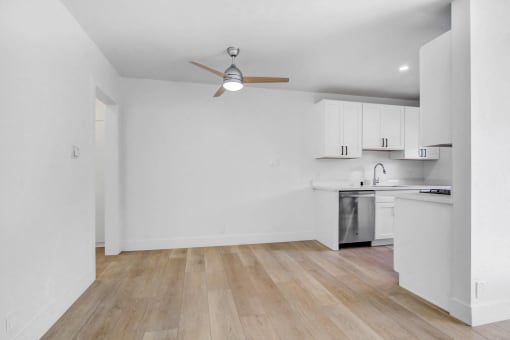 an empty kitchen with white cabinets and a ceiling fan