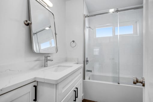 a white bathroom with a shower and a sink and a mirror