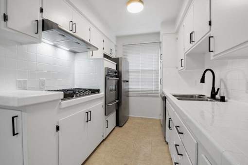 A kitchen with white cabinets and a black stove top.