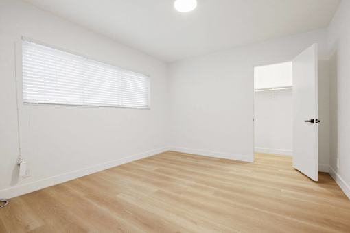 A room with wooden flooring and a window with blinds.