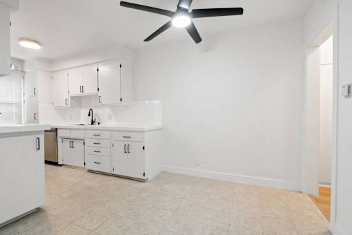 A white kitchen with a fan on the ceiling.