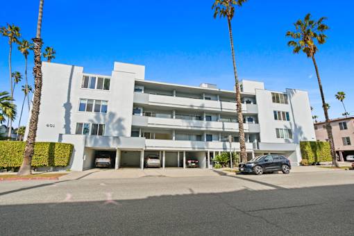 A modern white building with palm trees in front.