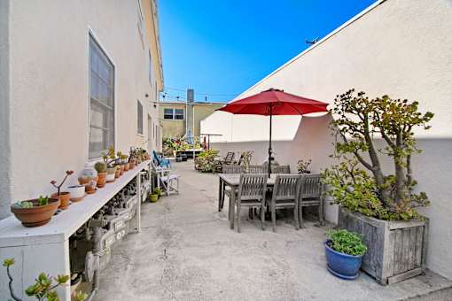 A patio with a table, chairs, and a red umbrella.