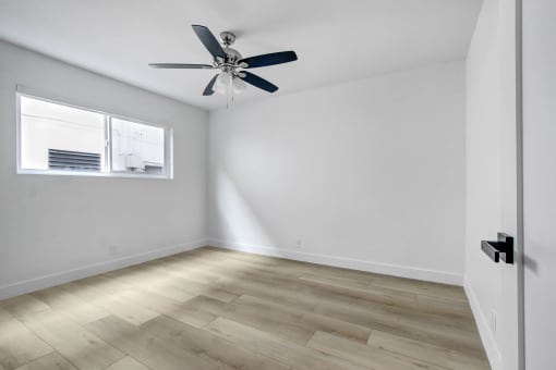 an empty room with white walls and a ceiling fan