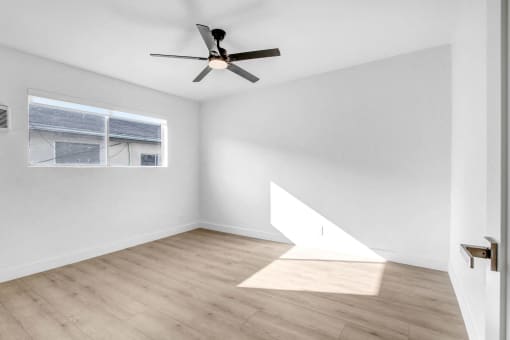 an empty room with white walls and a ceiling fan