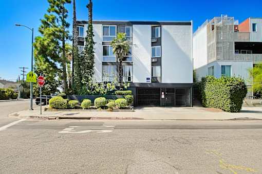 A street view of a building with a stop sign and a tree.