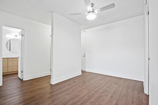 A room with a ceiling fan and wooden flooring.