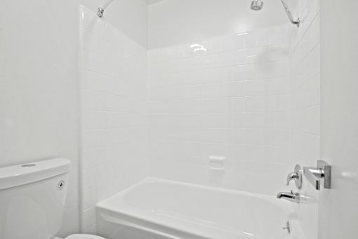 A white bathroom with a tub, toilet and sink.