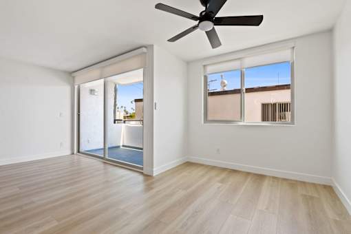 A room with a ceiling fan and sliding glass doors.