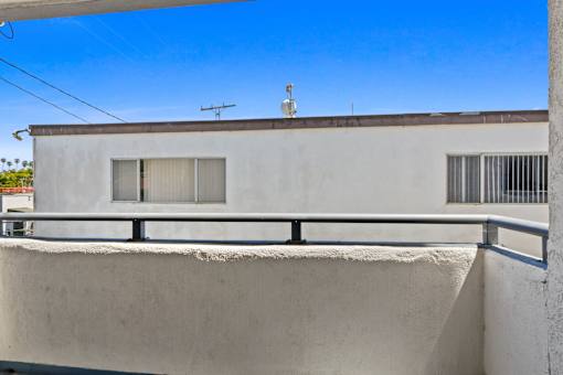 A white building with a balcony and a small antenna on top.